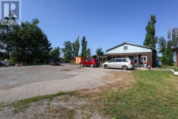 Metal-clad building with covered parking area and cars parked on a gravel lot. - 4175 Highway 35 N, Kawartha Lakes