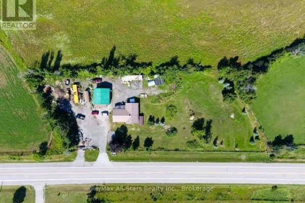 Aerial view of a property with a house, outbuildings, gravel yard, and surrounding green fields. - 4175 Highway 35 N, Kawartha Lakes