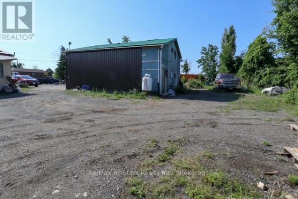 Exterior of a dark blue metal building with a green roof and a white propane tank in the yard. - 4175 Highway 35 N, Kawartha Lakes