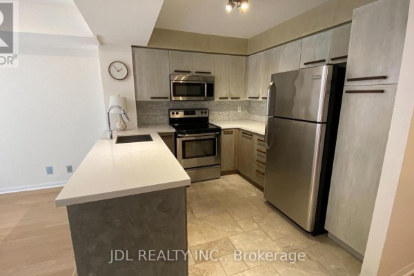 Kitchen with stainless steel appliances, light wood cabinets, and a breakfast bar. - 418 - 11 St Joseph Street, Toronto