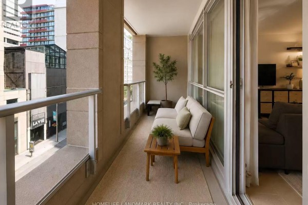 Balcony with outdoor seating, coffee table, and glass railings overlooking a city street. - 418 - 199 Richmond Street W, Toronto