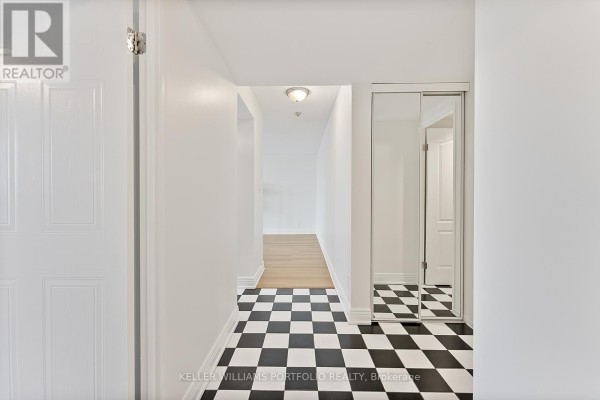 Apartment entrance hallway with black and white checkered tile floor and mirrored closet doors. - 418 - 2550 Lawrence Avenue E, Toronto