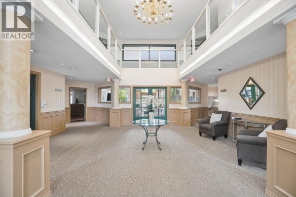Interior lobby with patterned carpet, beige walls, pillars, and glass doors. - 418 2995 Princess Crescent, Coquitlam