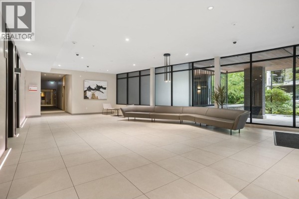 Spacious apartment building lobby with light tile floors and modern seating. - 418 3581 Ross Drive, Vancouver