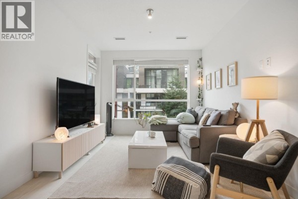 Living room with a grey sectional sofa, coffee table, and large window. - 418 3581 Ross Drive, Vancouver
