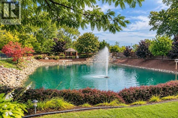 Scenic view of a pond with a fountain, surrounded by trees and landscaping. - 418 Cooper Crescent, Lakeshore