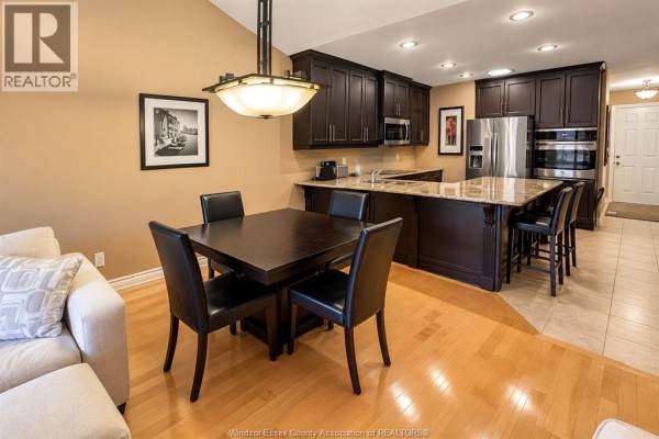 Dining area with a dark wood table and chairs adjacent to a modern kitchen. - 418 Cooper Crescent, Lakeshore