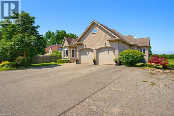 Side view of a brick bungalow featuring a double garage and landscape plantings. - 4188 Victoria Avenue, Vineland Station