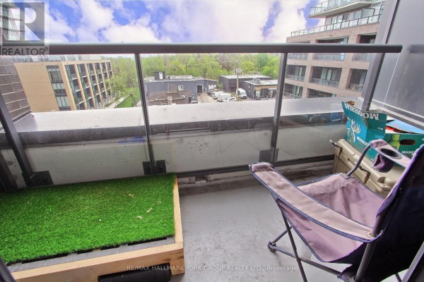 Balcony with a chair, artificial grass patch, and view of buildings and trees. - 419 - 185 Deerfield Road, Newmarket