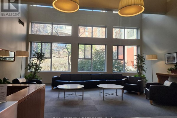 Building lobby seating area with dark leather couches and round coffee tables. - 419 - 222 The Esplanade, Toronto