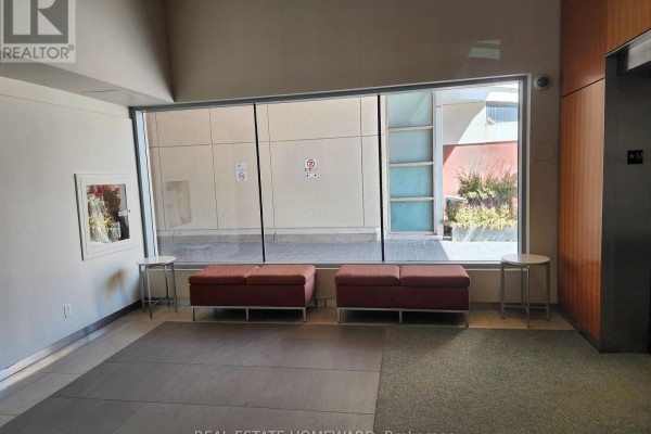 Building hallway with modern benches and a large window overlooking courtyard. - 419 - 222 The Esplanade, Toronto
