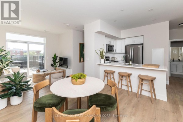 Open concept dining area with light wood flooring, white island with bar stools, and dining set. - 419 - 230 North Centre Road, London North
