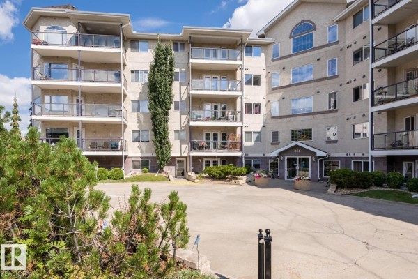 Apartment building lobby with tiled floors, black leather chairs, and a wooden table. - #419 261 Youville Dr Nw, Edmonton