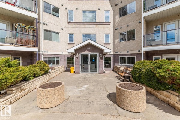 Interior hallway of an apartment building with carpeted floors and a wooden staircase. - #419 261 Youville Dr Nw, Edmonton