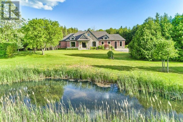 Residential property featuring a brick home and a small pond with reeds. - 4199 Highway #2, Clarington