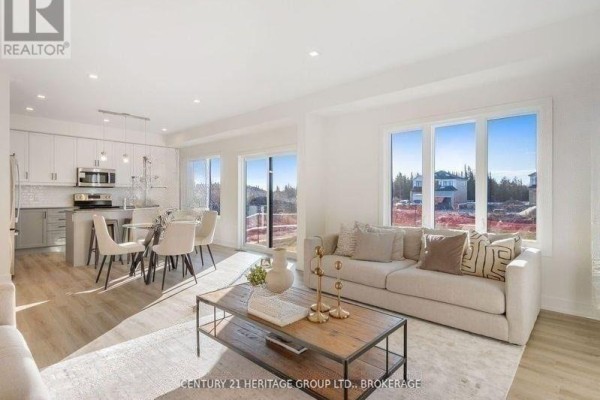 Open-concept living and dining area with beige sofas, a wooden coffee table, and large windows. - 42(lot 20) Dusenbury Drive, Loyalist