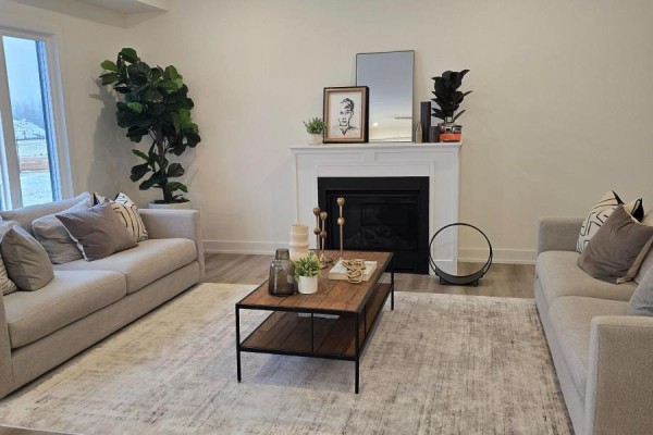 Living room with a white fireplace, two beige sofas, and a rustic wooden coffee table. - 42(lot 20) Dusenbury Drive, Loyalist