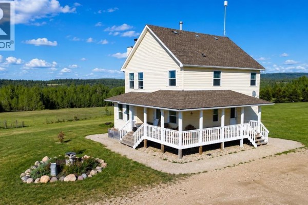 Side view of a yellow two-story house with a covered front porch and white railings. - 42, 113033 Township Road 592, Rural Woodlands County