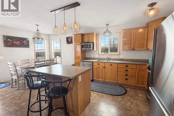 Kitchen with light wood cabinets, stainless steel appliances, and a central island with seating. - 42, 113033 Township Road 592, Rural Woodlands County