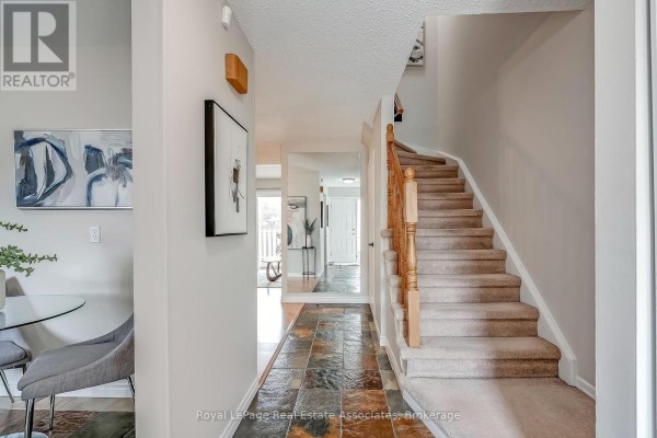 Interior entryway with slate tile floor, carpeted stairs, and artwork. - 42 - 2779 Gananoque Drive, Mississauga