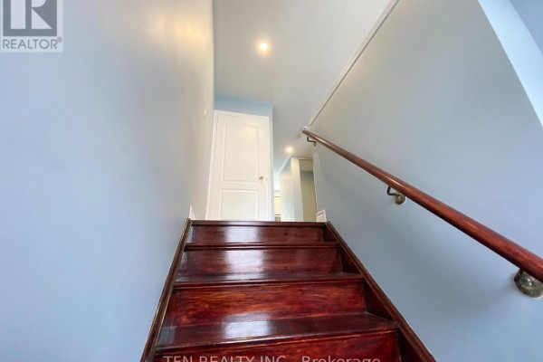 View from a lower staircase looking up towards a landing and a closed white door. Light blue walls. - 42 - 3020 Cedarglen Gate, Mississauga