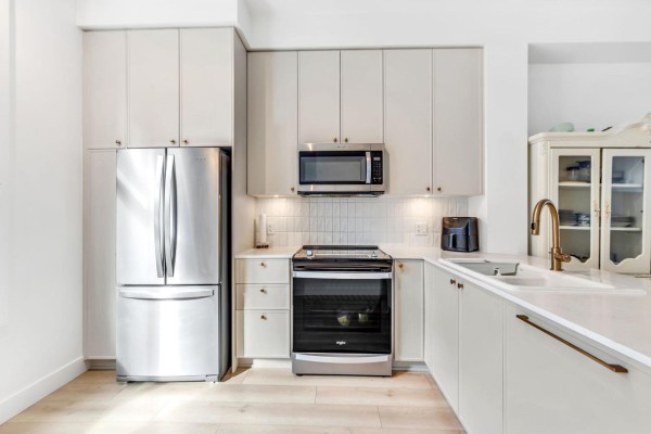 Kitchen features stainless steel refrigerator, oven, microwave, and white countertops. - 42 14151 58a Avenue, Surrey
