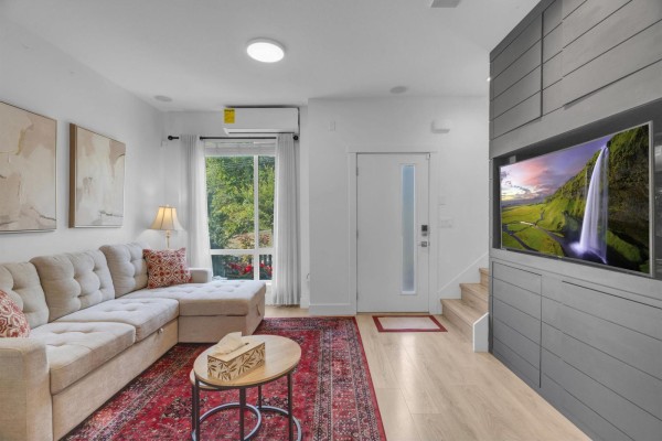 Living room with sectional sofa, entertainment unit with television, and doorway. - 42 16433 19 Avenue, White Rock