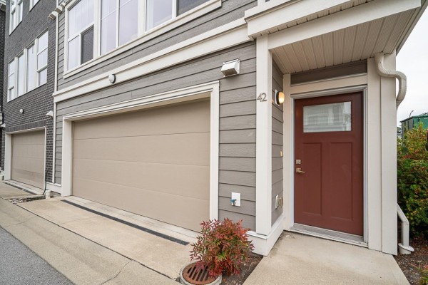 Close-up of the townhouse entrance with a brown door, large garage door, and address number 42. - 42 8372 202b Street, Langley
