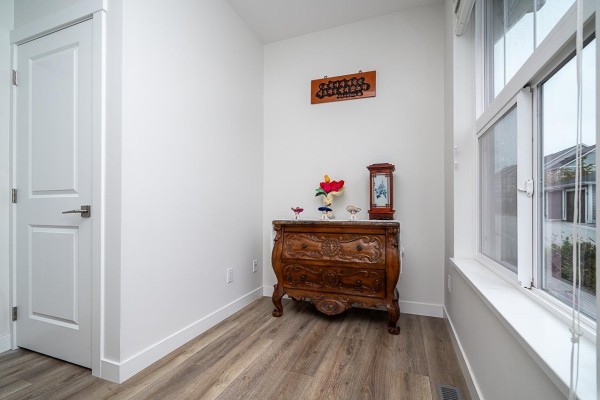 Entryway with white door, wooden dresser with decorative items, and a window with blinds. - 42 8372 202b Street, Langley