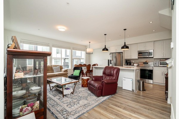 Living room and kitchen with a burgundy leather recliner, sofa, dining table, and light grey cabinets. - 42 8372 202b Street, Langley