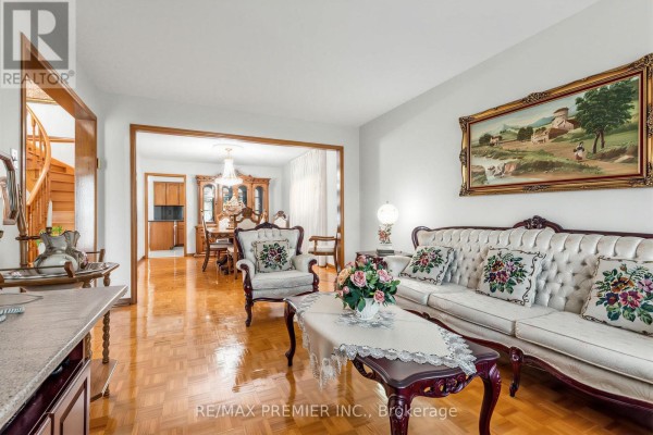Living room with white tufted sofa, ornate armchair, coffee table, and dining room view. - 42 Burgosa Court, Vaughan