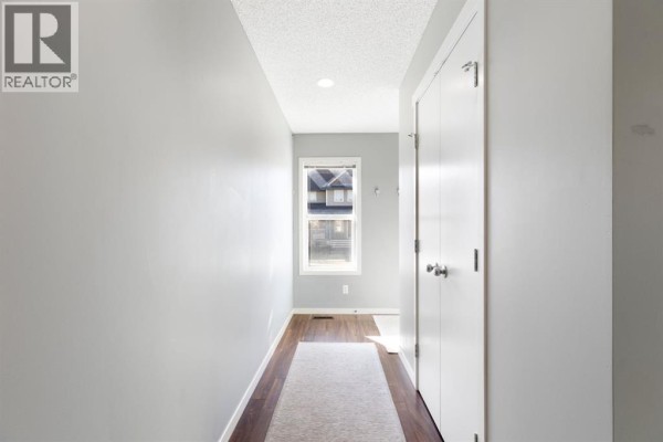 View down a narrow hallway with grey walls and white double doors, leading to a window. - 42 Copperpond Place Se, Calgary