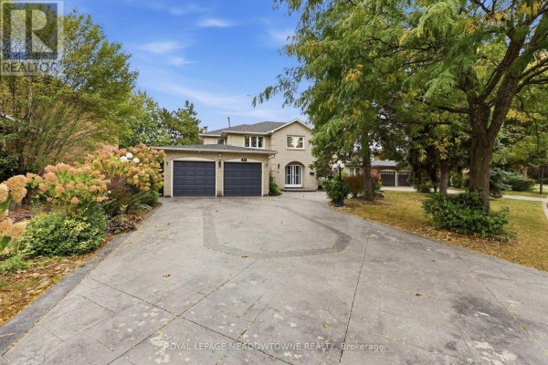 Wide view of house exterior, driveway, and landscaping with trees. - 42 Dawnridge Trail, Brampton