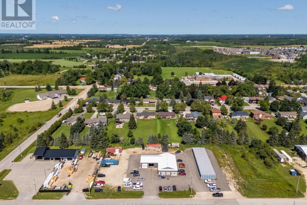Wide aerial view of commercial property surrounded by residential homes, green fields, and distant treeline. - 42 Hanbury Street, Southgate