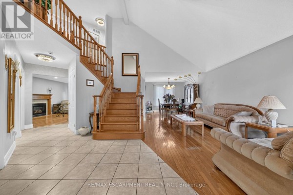 Entryway showcasing wooden staircase, tile and hardwood flooring, and a cozy seating area. - 42 Hillgarden Drive, Hamilton