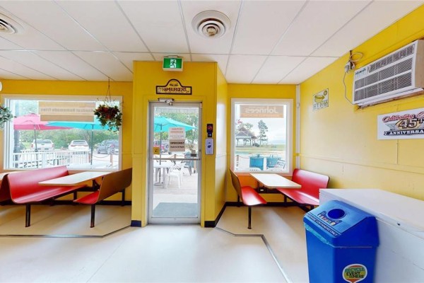 Dining area with yellow walls, red booths, tables, and view of outdoor seating. - 42 Main Street, Winnipeg Beach