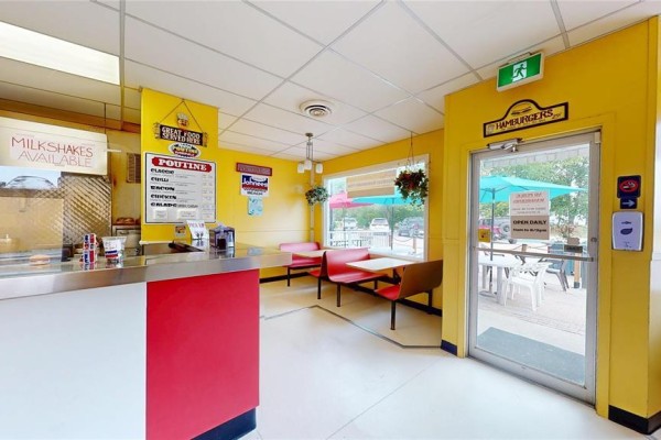 View of the counter and dining area with yellow walls and red booths. - 42 Main Street, Winnipeg Beach
