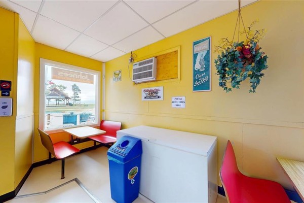 Corner seating area with yellow walls, red chairs, a freezer, and window view. - 42 Main Street, Winnipeg Beach