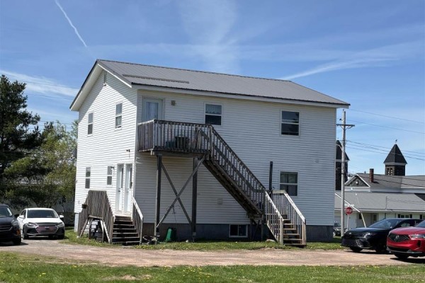 Two-story white vinyl-sided multi-family house with an external wooden staircase connecting two floors. - 42 Pleasant Street, Springhill