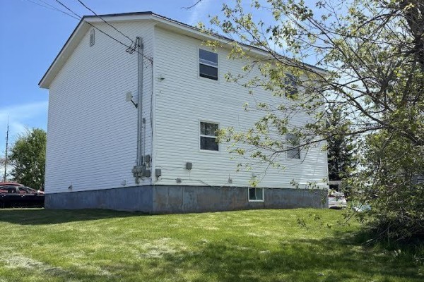 Side view of the white vinyl-sided multi-family house showing its foundation and windows. - 42 Pleasant Street, Springhill