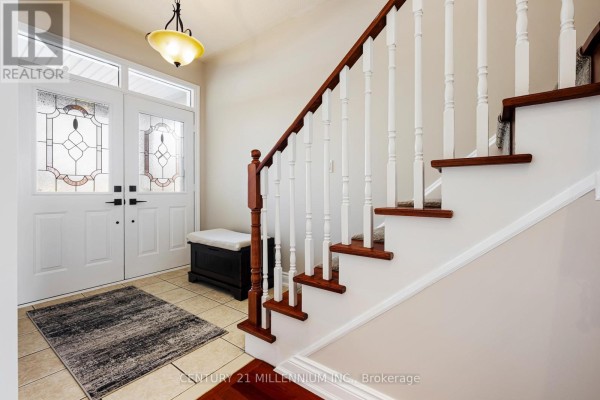 Welcoming foyer with double doors, tiled floor, and staircase with wooden railing. - 42 Rubysilver Drive, Brampton
