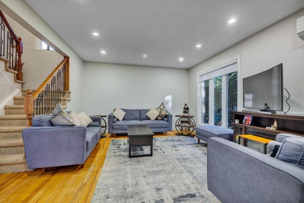 Living room with hardwood floors, grey sofas, a coffee table, and a television visible. - 42 Rue De Loranger, Gatineau