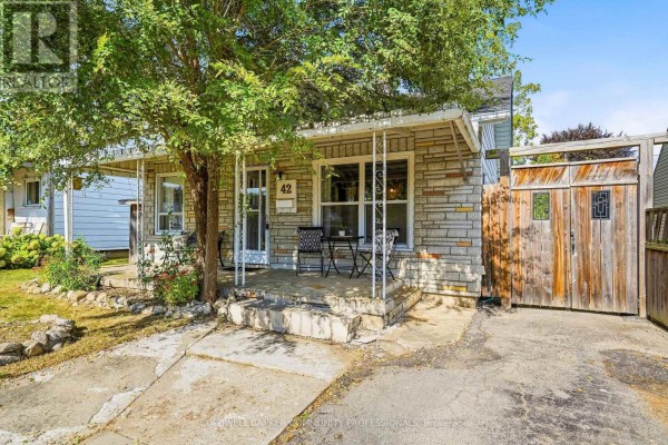Close-up view of the house entrance with a covered porch, stone exterior, and a small bistro set. - 42 Sanderson Street, Brantford