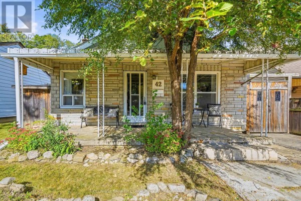 Front porch of the house with seating, stone exterior, and a tree in front. - 42 Sanderson Street, Brantford