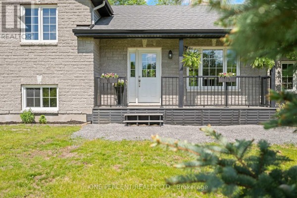 Close-up of the front porch with a white door, black railings, and potted plants. - 42 Stonewalk Drive, North Grenville