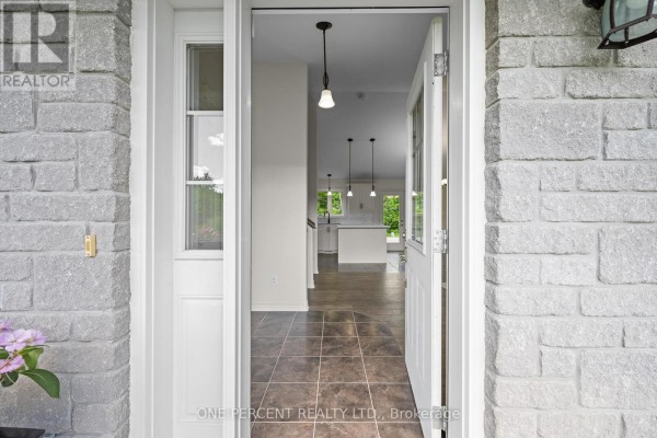 View through the open front door into a hallway leading to a white kitchen. - 42 Stonewalk Drive, North Grenville
