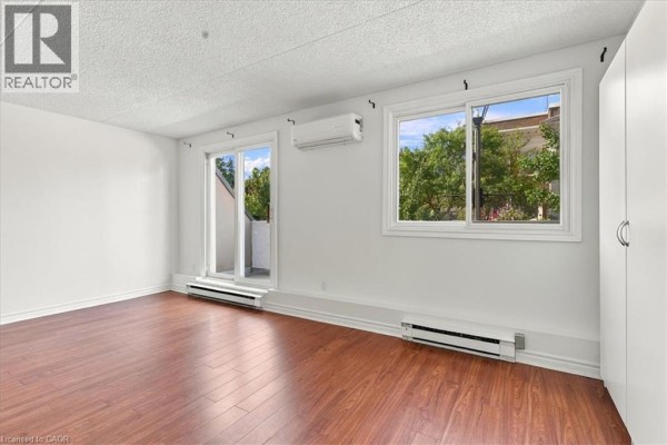 Room with wood flooring, windows, sliding glass door to balcony, and storage closet. - 42 Tannery Street E Unit# 246, Cambridge