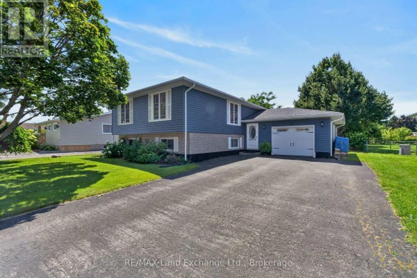 Side exterior view of a blue sided house with a double garage door and asphalt driveway. - 42 Webster Street, Kincardine