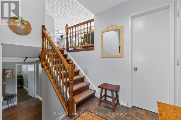 Interior view of a stairwell with a wooden banister and carpeted steps, leading to the main floor. - 42 Webster Street, Kincardine