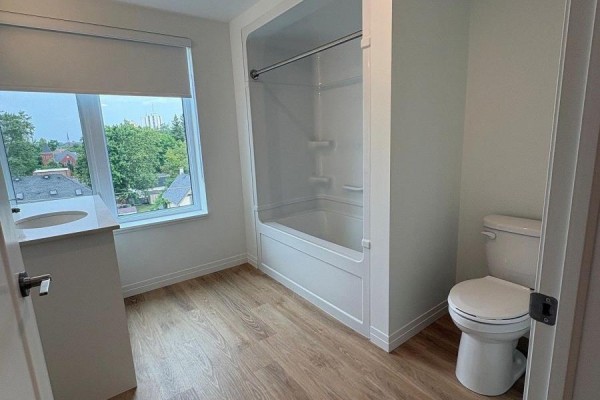 Small bathroom with a white toilet, white bathtub and shower surround, and a vanity with a sink. - 420 - 351 Hill Street, London East